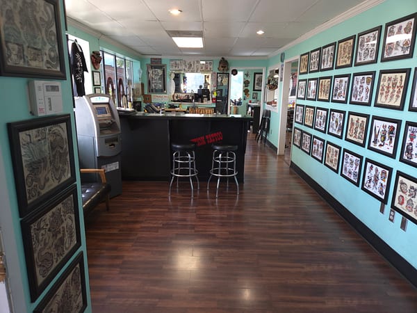 Reception counter at Evolution Tattoo beneath a wall of framed flash art