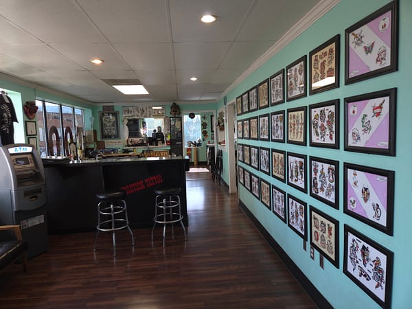 Front lobby with barstools and framed tattoo flash covering the walls