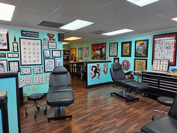 Open studio floor with tattoo stations and walls of framed flash art