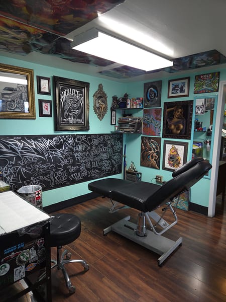 Tattoo station beside a chalkboard mural and framed original art