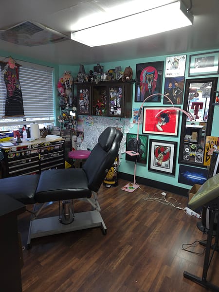 Tattoo station with rolling equipment tray and portrait artwork